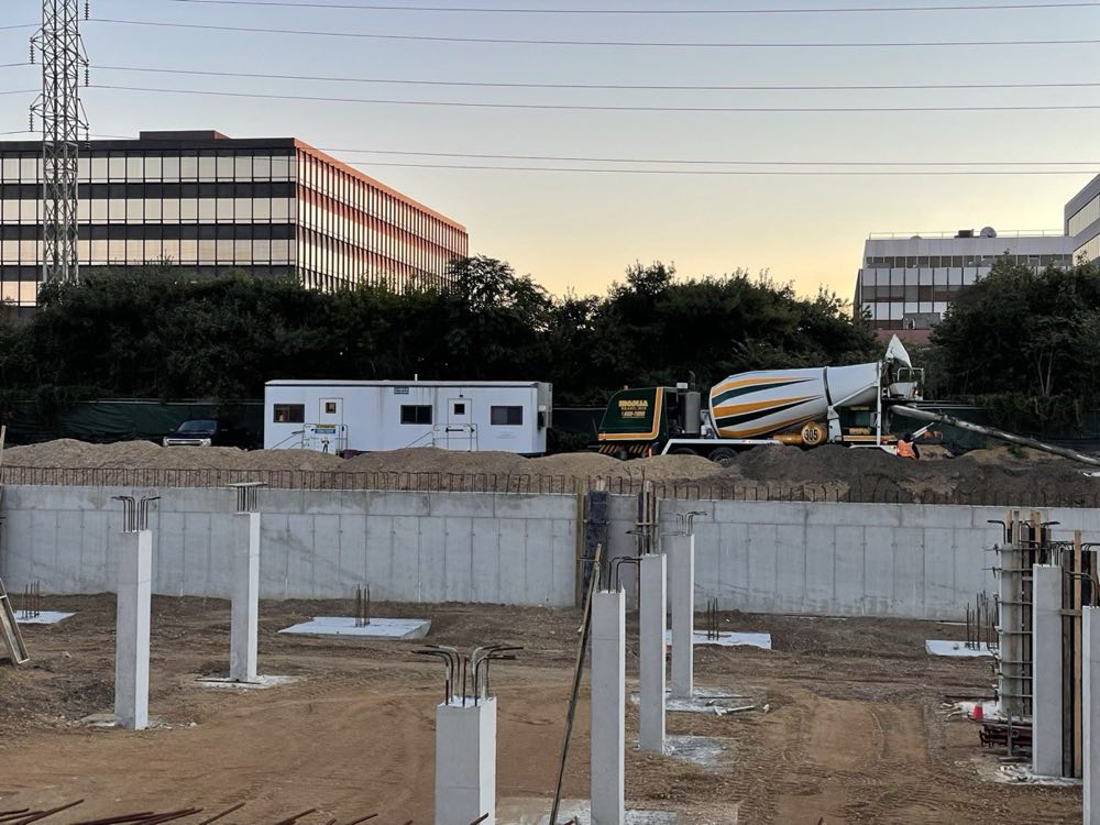 Poured foundation walls and column bases at dusk with a Nicolia mixer on site