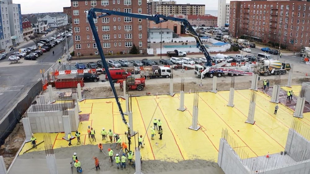 Aerial view of an insulated slab pour with a concrete pump boom