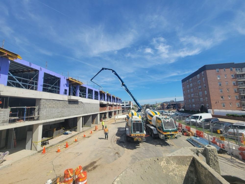 Concrete pump boom placing a deck at a mid-rise building with Nicolia mixers feeding the pump