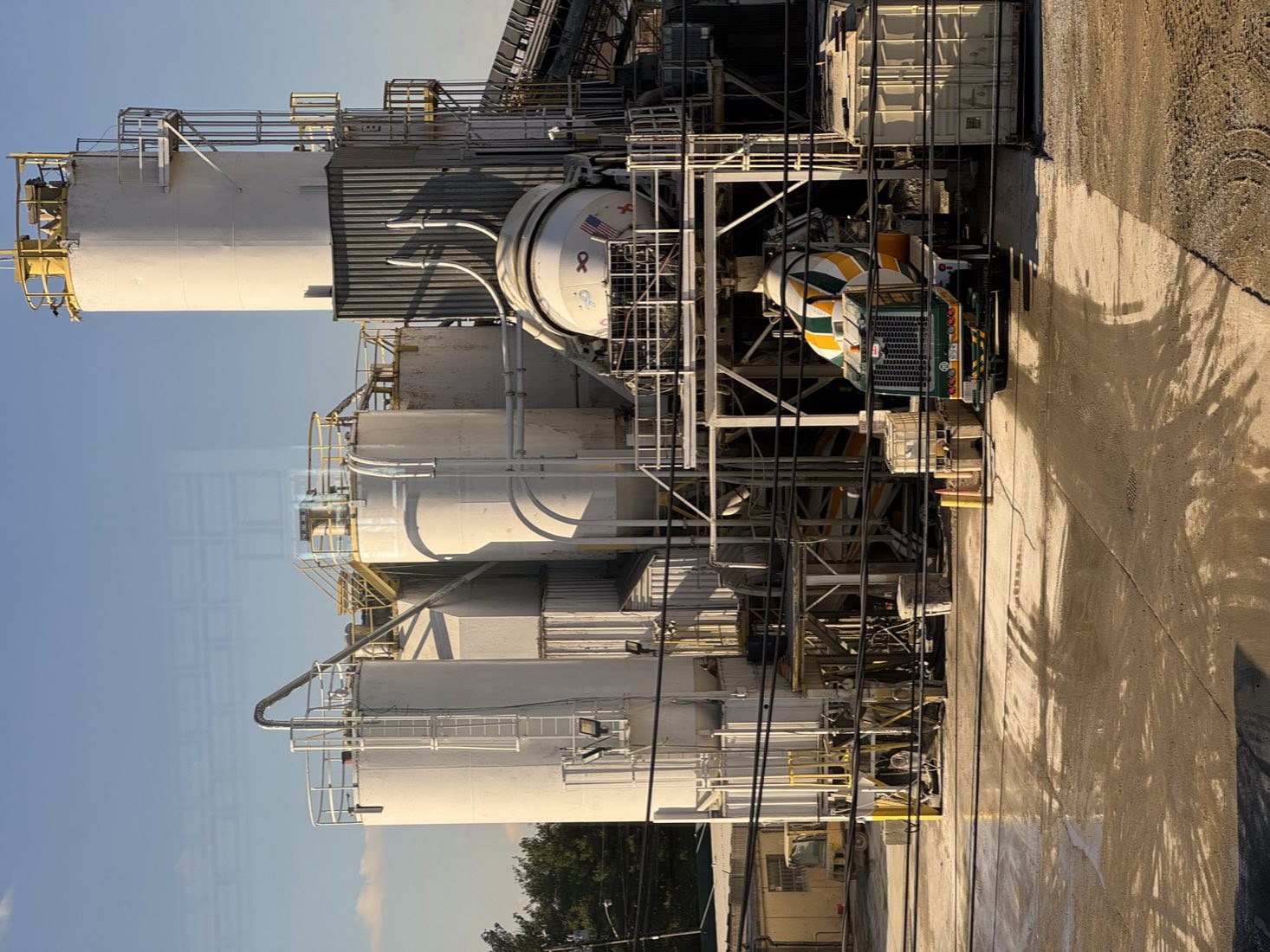 The Nicolia central mix plant at Westbury with white silos and a front-discharge mixer loading under the plant