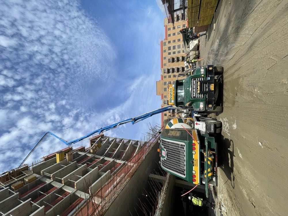 Concrete pump boom and Nicolia mixer trucks working a jobsite