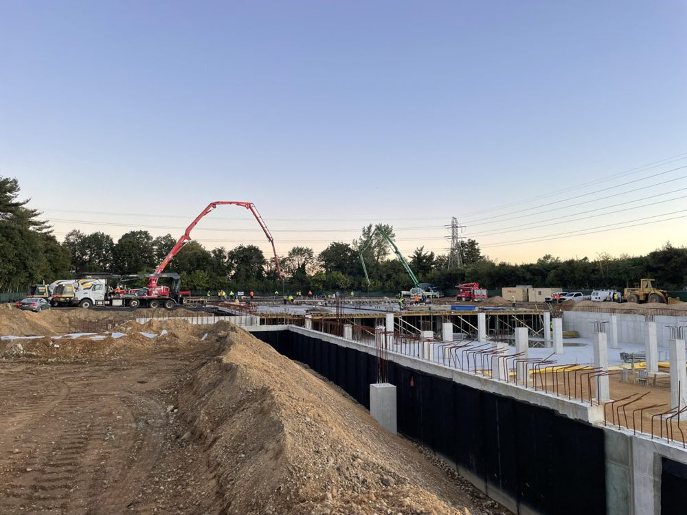 Concrete pump boom placing a structural deck above poured foundation walls
