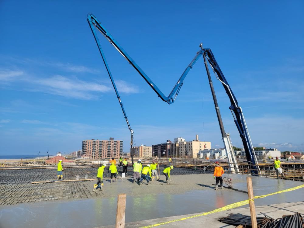 Two pump booms and crew placing a large concrete deck