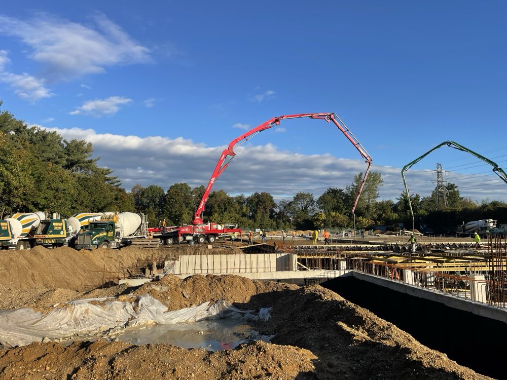 Two concrete pump booms placing at a foundation site