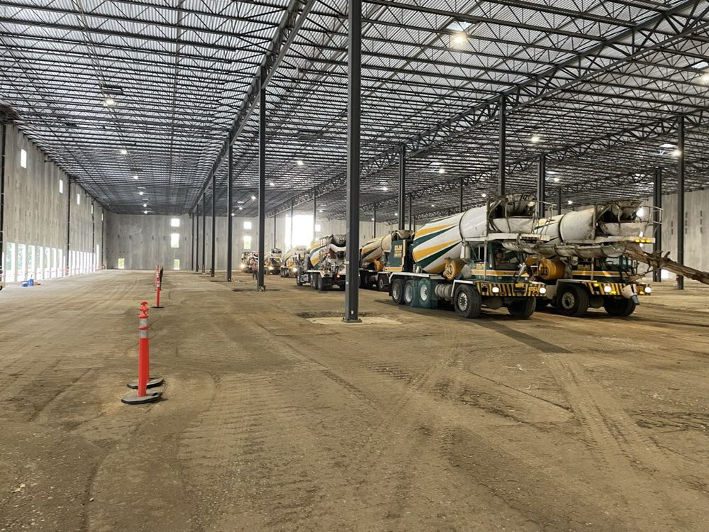 Two Nicolia front-discharge mixers staged inside a warehouse shell ahead of a slab pour